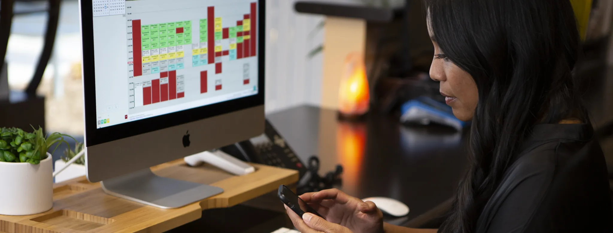 woman sitting at desk working on her phone