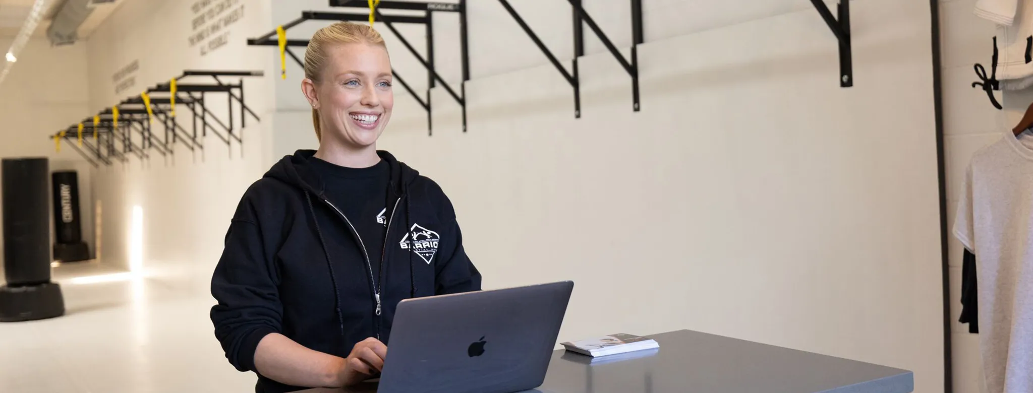 Woman works on her laptop at fitness studio front desk