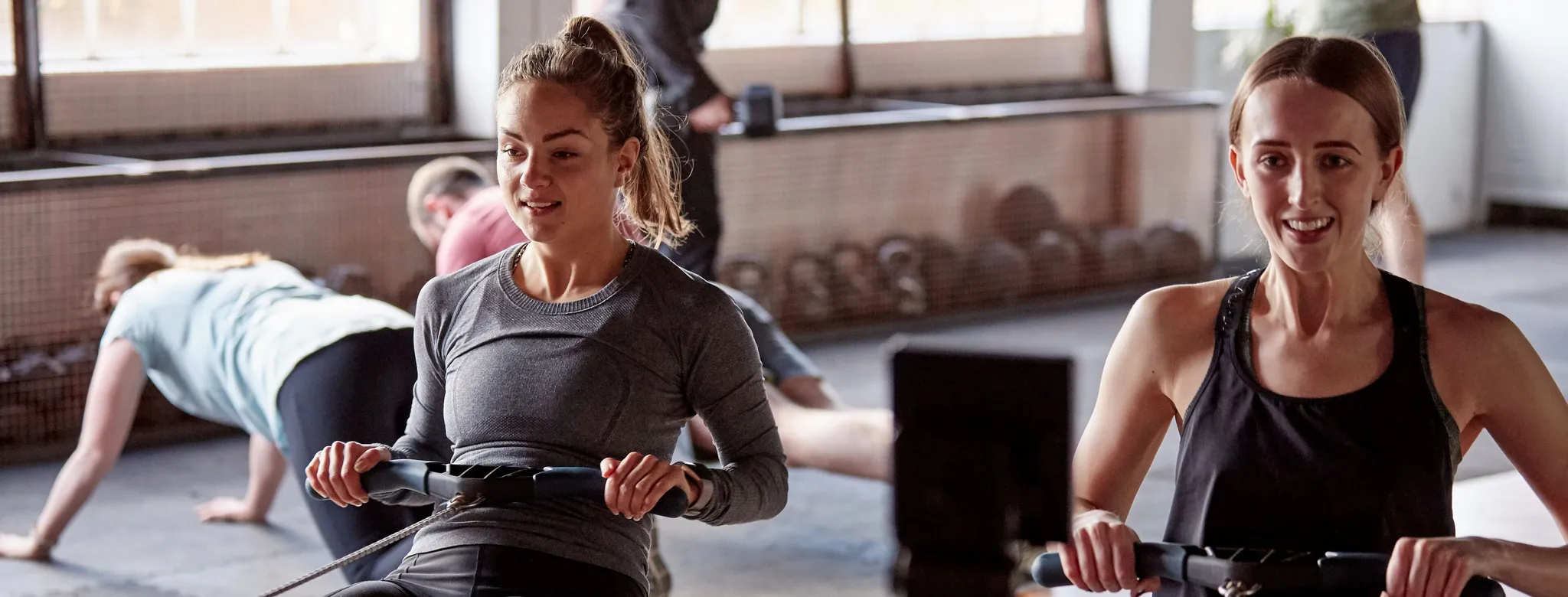 Two women work out on rower machines