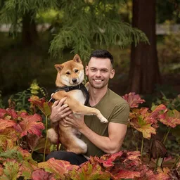 Man with dog posing with leaves and tree
