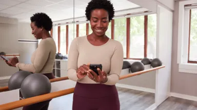 A woman using a phone in a barre studio