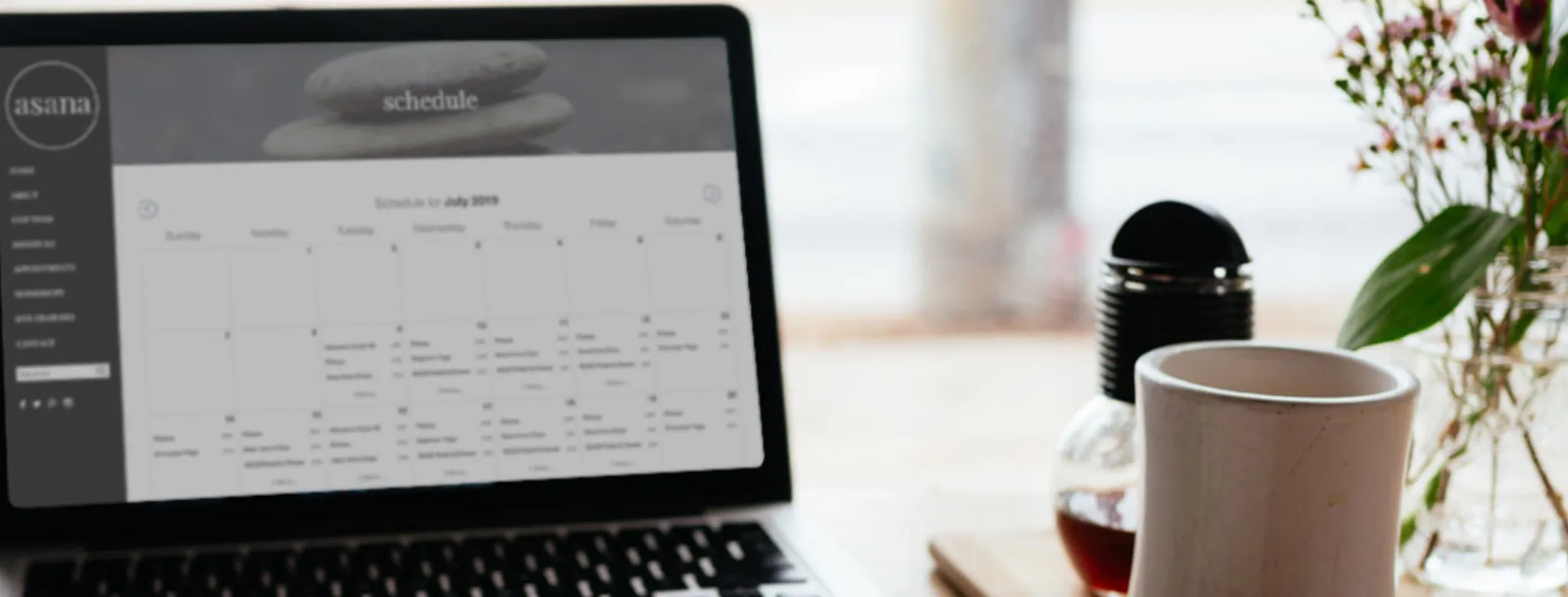 schedule on laptop on a desk with coffee and flowers