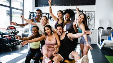 Eight people smiling posing for a picture at a gym