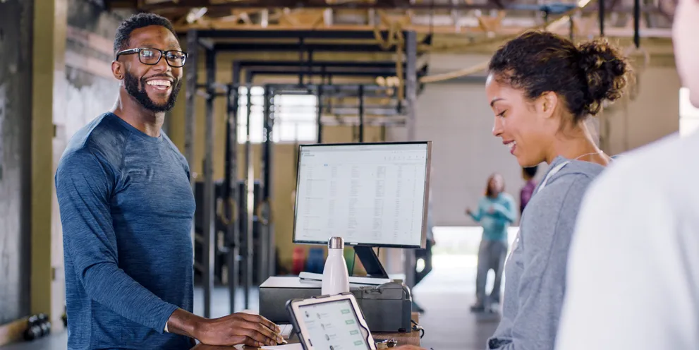 Man at front desk greeting a customer on an iPad