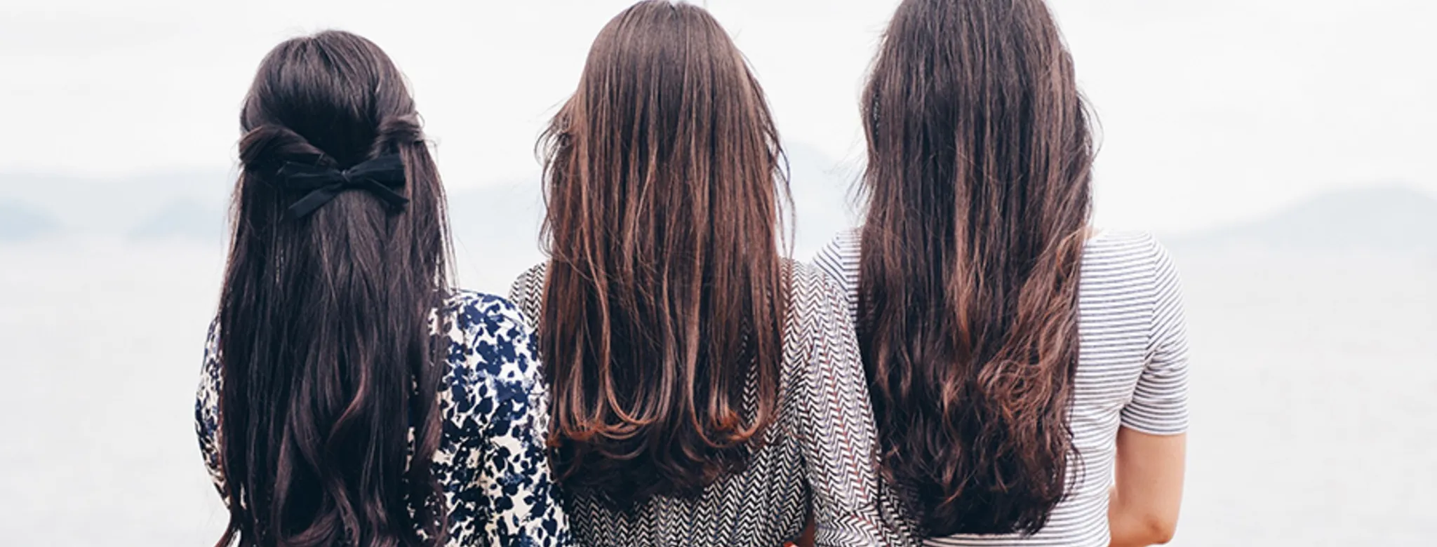 three women with brown hair standing outside