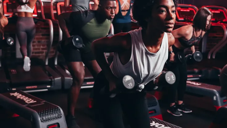 A woman doing dumbbell rows at Kyle House Fitness 