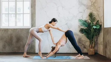 Yoga owner teaching a downward dog pose to student on their mat
