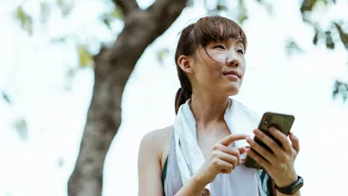 runner on phone outside reading about wellness trends