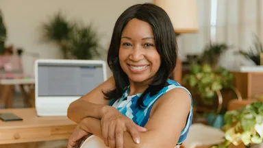 Business owner sitting in chair near computer using Mindbody Payments