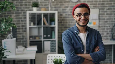 Salon owner smiling in blue shirt and red hat