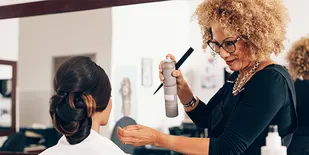 Stylist spraying hairspray on client's updo
