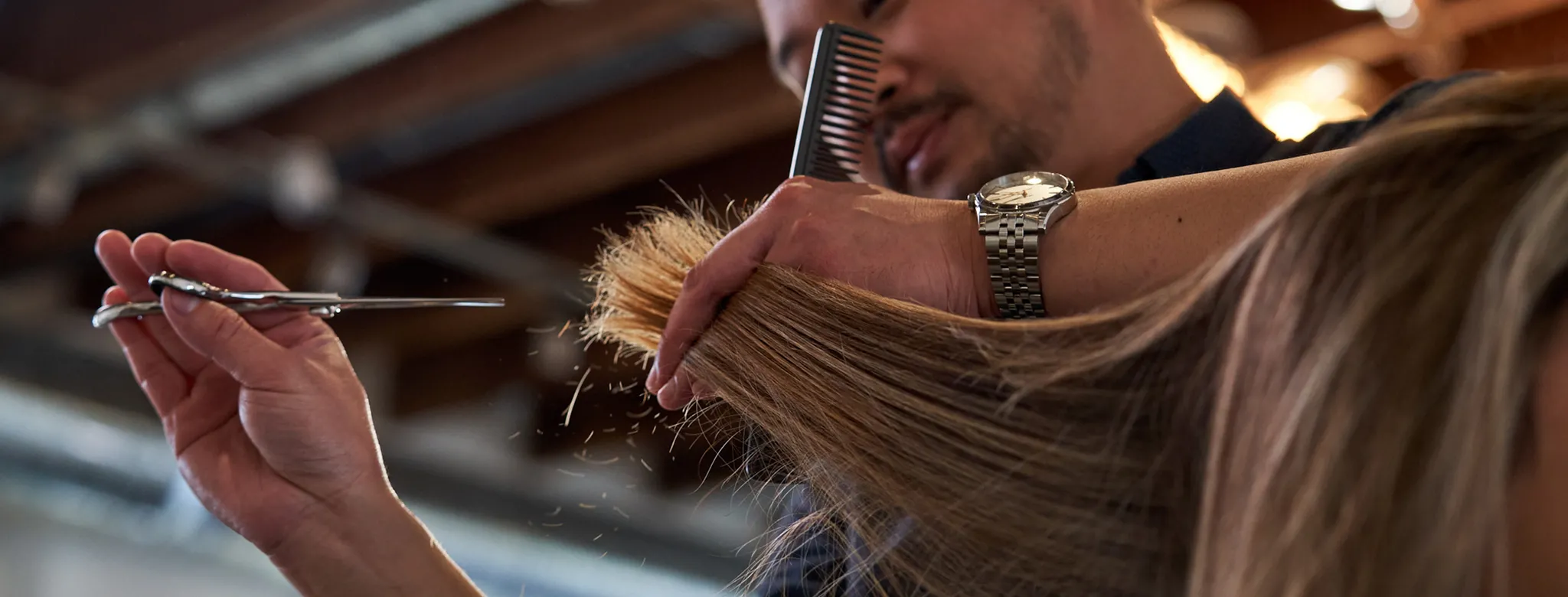 Man cutting blond woman's hair with scissors