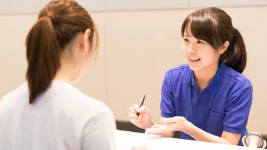 Woman in blue shirt at gym front desk showing AI assistant to client in white shirt