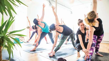 Yoga instructor helping with modifications in a yoga class
