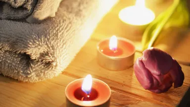 Candles and rose by folded towels