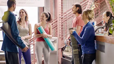 Group of clients with yoga mats standing by front desk