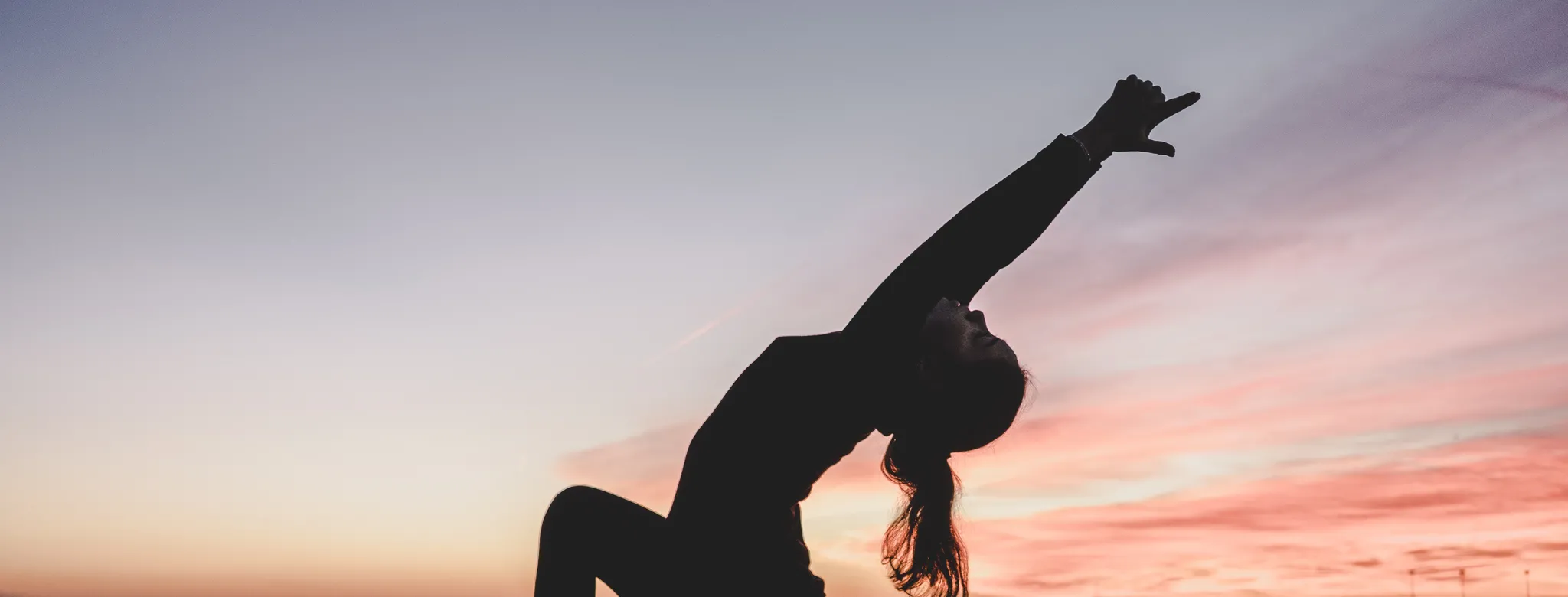 Women practicing yoga in front of sunset