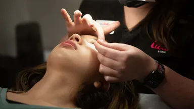 A woman getting her eyelashes done at a salon.