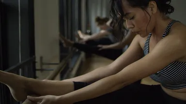 woman in striped sports attire doing barre